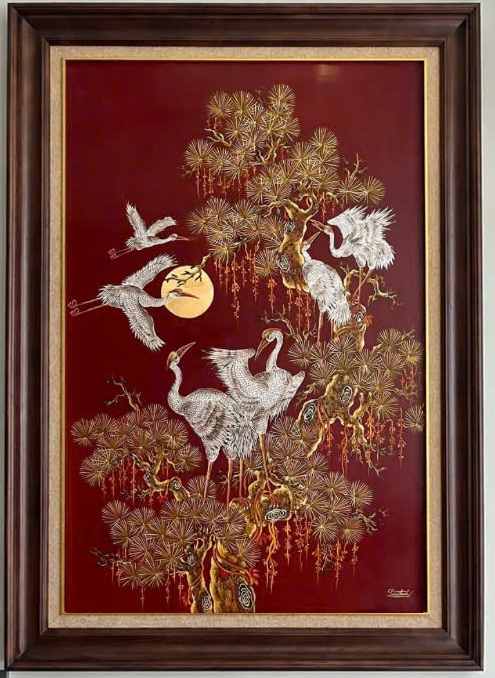 Tùng hạc diên niên — White cranes gather around a pine tree against a deep red ground. Gold-toned needles and branches give this vertical composition a delicate, luminous rhythm.