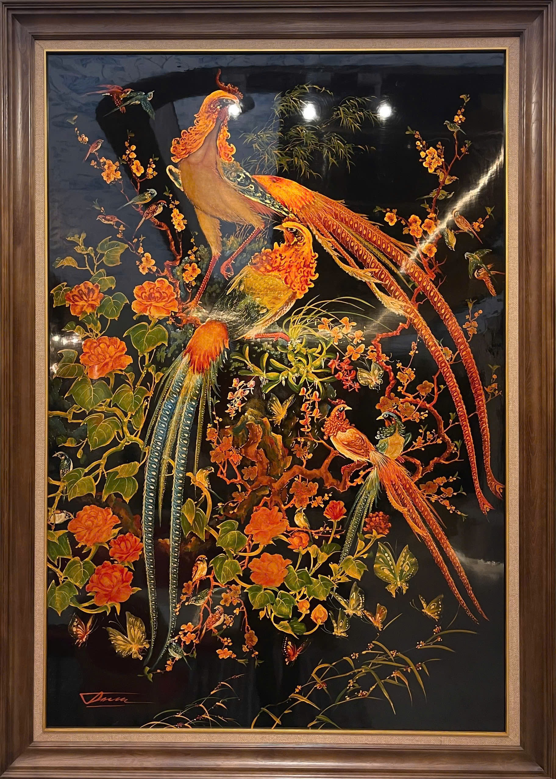 Phượng hoàng — Long-tailed birds, flowering branches and butterflies rise through a vertical black-ground composition. Orange and gold-toned details give the work its striking contrast.