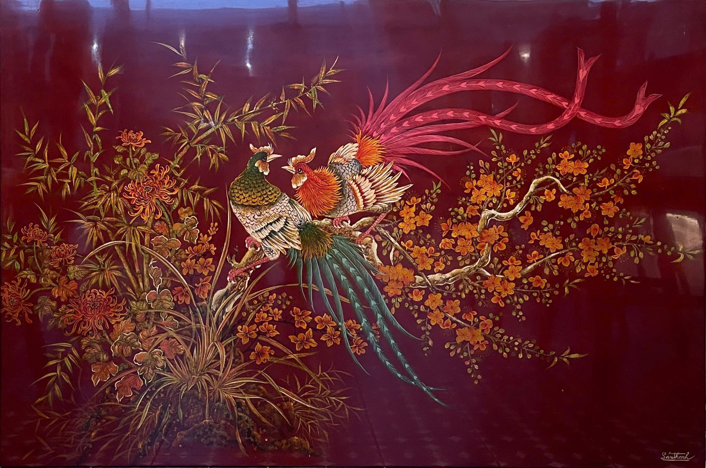 Chim trĩ và hoa mai — A pair of long-tailed pheasants perch among apricot blossoms and bamboo. Their red and green plumage sweeps across a deep red ground.